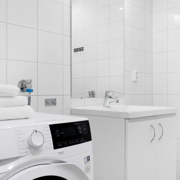 Moderne bad med vaskemaskin, vask med lagringsplass under og et speil