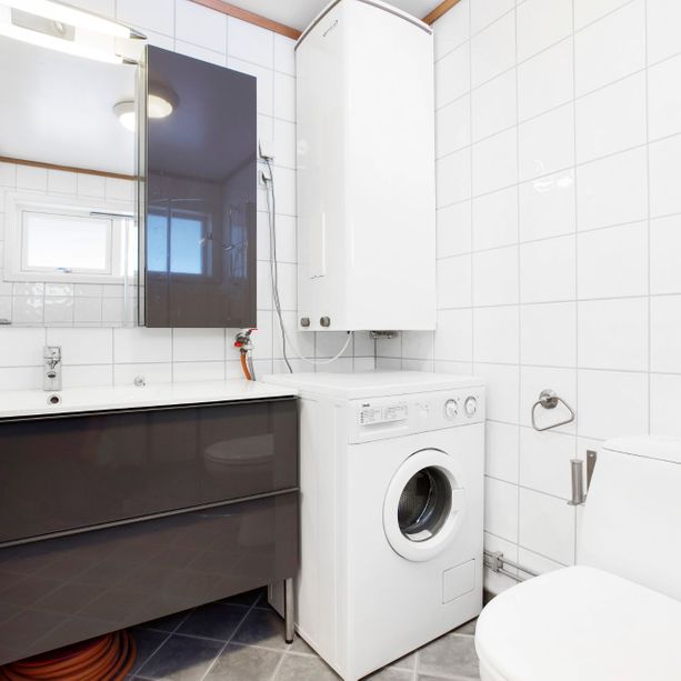 Moderne bad med vaskemaskin, skap med speil, bred vask med skuffer og toalett